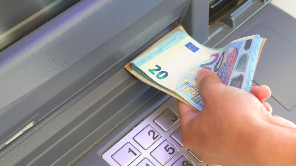 Een afbeelding van iemand die euro bankbiljetten uit een pinautomaat trekt