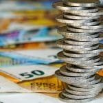 Een afbeelding van een stapel 2 euro munten op briefgeld _ bankbiljetten