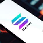 Een afbeelding van het Solana (SOL) logo op een mobiele telefoon met een koers op de achtergrond