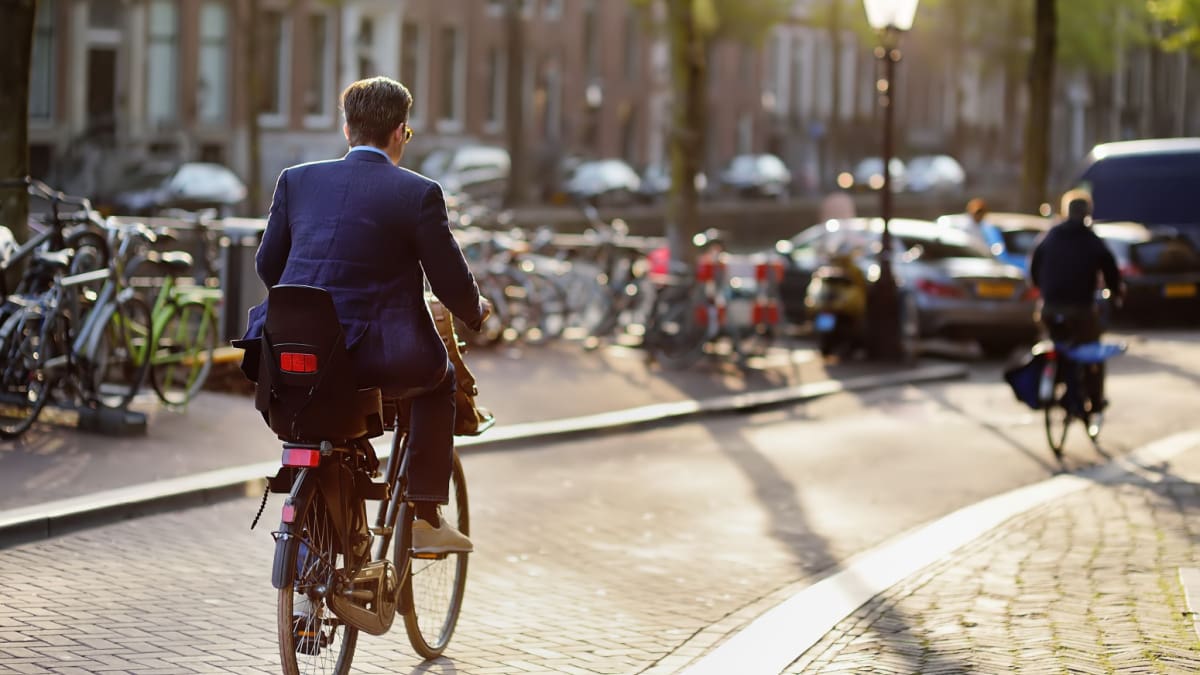 Een elegant geklede man rijdt op een fiets in het centrum van Amsterdam