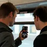 2 mannen kijken op telefoon dalende bitcoin koers (1)