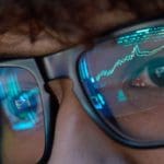 Een afbeelding van een jonge crypto investeerder die naar scherm kijkt meet een stijgende grafiek