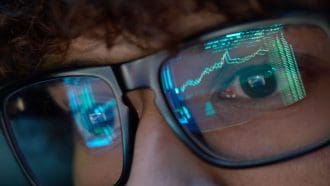 Een afbeelding van een jonge crypto investeerder die naar scherm kijkt meet een stijgende grafiek