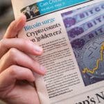 Een afbeelding van een krant met daarop nieuws over crypto en bitcoin die hard aan het stijgen zijn