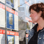 Vrouw bekijkt woningen bij makelaar