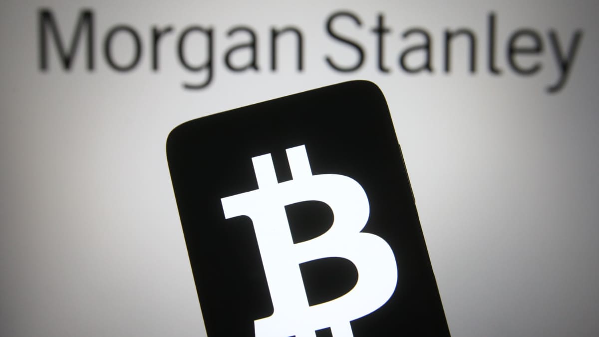 Een afbeelding van bankgigant Morgan Stanley op de achtergrond en op de voorgrond een mobiele telefoon met het bitcoin (BTC) logo