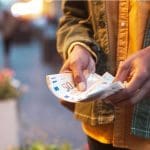 Een afbeelding van een man die euro bankbiljetten van 50 euro vasthoudt in zijn handen