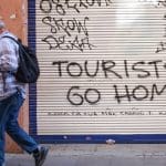 Een afbeelding van grafitti op een garagedeur in Barcelona tegen toerisme door overtoerisme en een woningcrisis