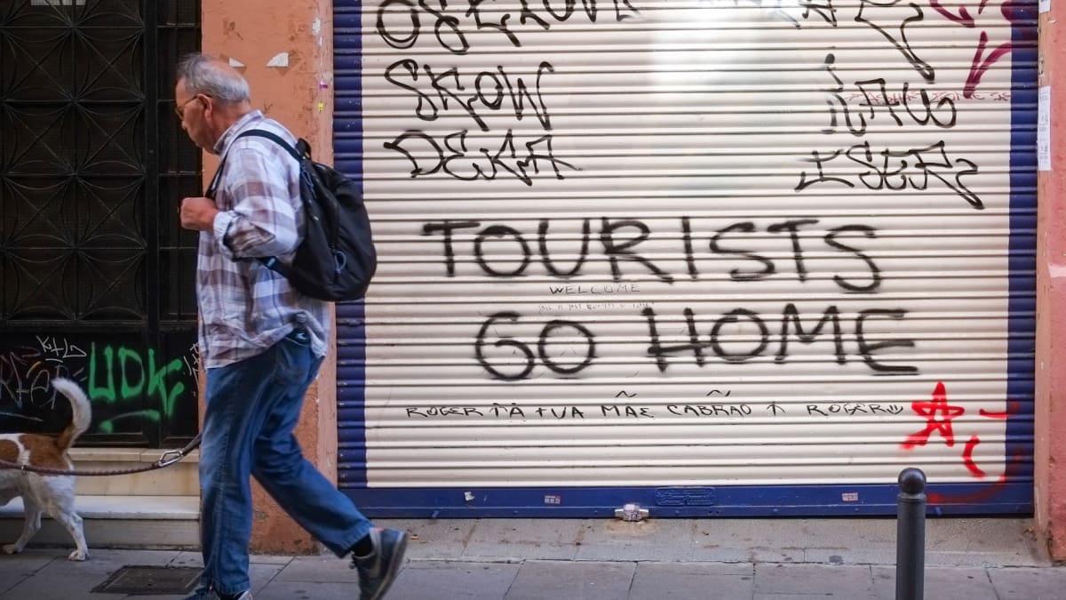 Een afbeelding van grafitti op een garagedeur in Barcelona tegen toerisme door overtoerisme en een woningcrisis