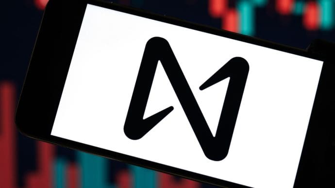 Een afbeelding van het logo van cryptoproject NEAR protocol met op de achtergrond schommelende koersen