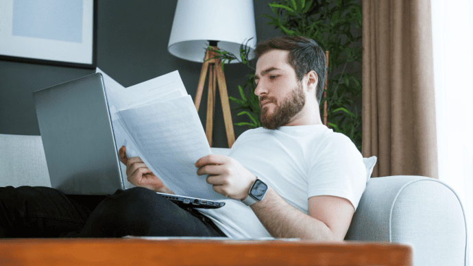 Man zit achterover met papieren en laptop