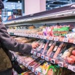 Nederlander pakt plakjes worst in de Albert Heijn