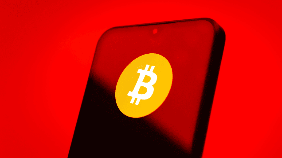 bitcoin logo op telefoon met rode achtergrond