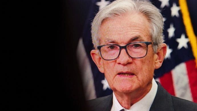 Een afbeelding van Jerome Powell met een Amerikaanse vlag op de achtergrond