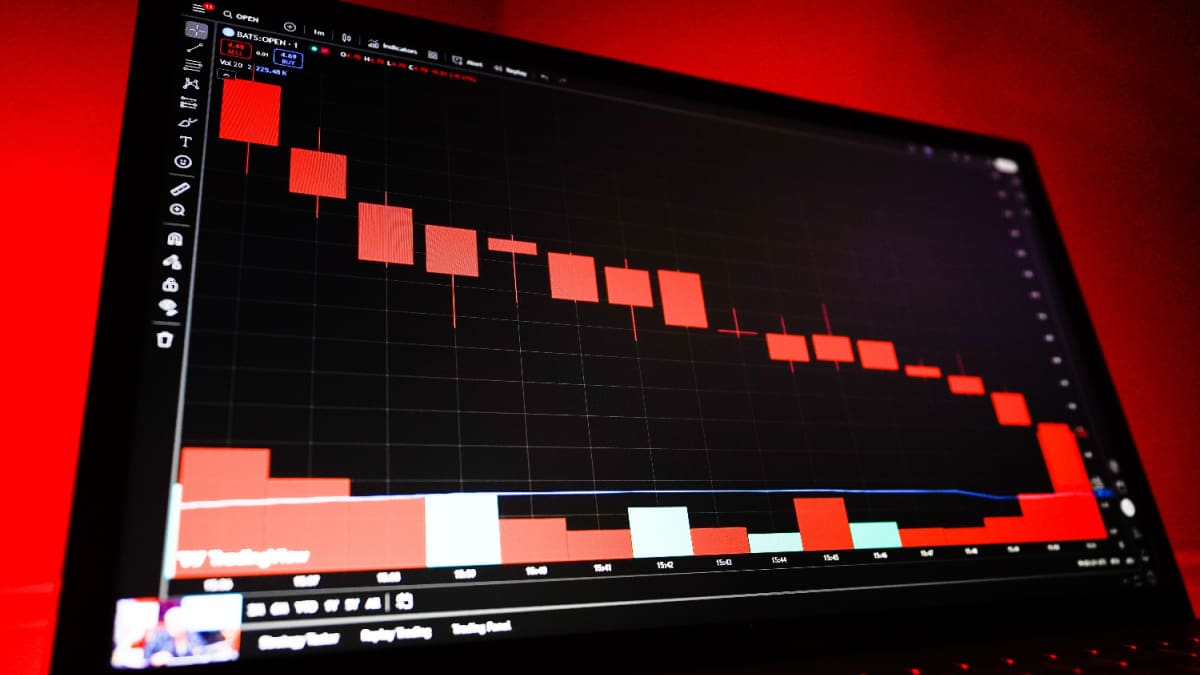 Een afbeelding van een dalende rode grafiek met marktdata op een computerscherm