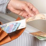 Een afbeelding van een hand die bankbiljetten uit een portemonnee haalt en op een verwarming legt