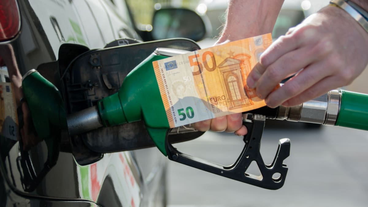 Een afbeelding van een man die aan het tanken is met een vijftig euro briefje in zijn hand