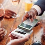 Een afbeelding van een man die met zijn mobiel betaalt in een restaurant