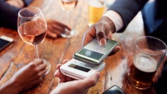 Een afbeelding van een man die met zijn mobiel betaalt in een restaurant