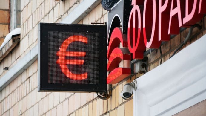 Een afbeelding van een rode euro op een bord bij een wisselkantoor