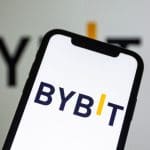 Een afbeelding van het Bybit logo op een mobiele telefoon en op de achtergrond