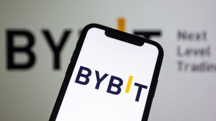 Een afbeelding van het Bybit logo op een mobiele telefoon en op de achtergrond