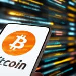 Een afbeelding van het bitcoin (BTC) logo op een mobiele telefoon