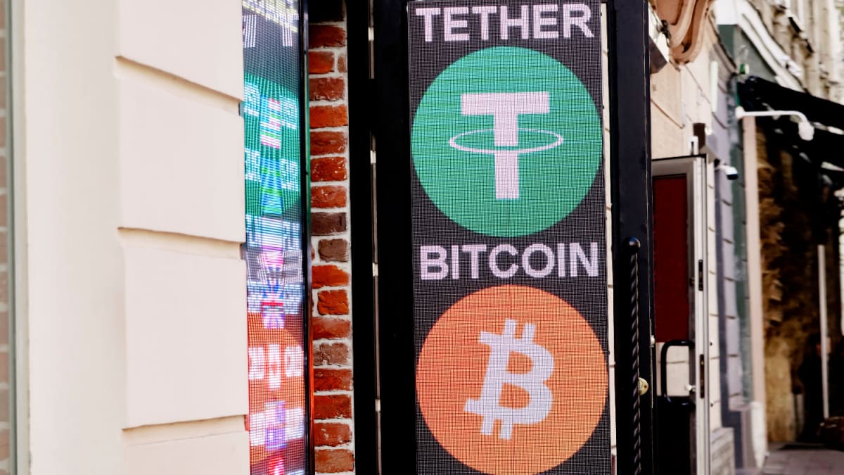 Een afbeelding van het tether logo op een uithangbord met daaronder het logo van bitcoin (BTC)