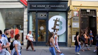 Een afbeelding van 'the house of nakamoto' met een bitcoin logo op de gevel van een winkel _ huis