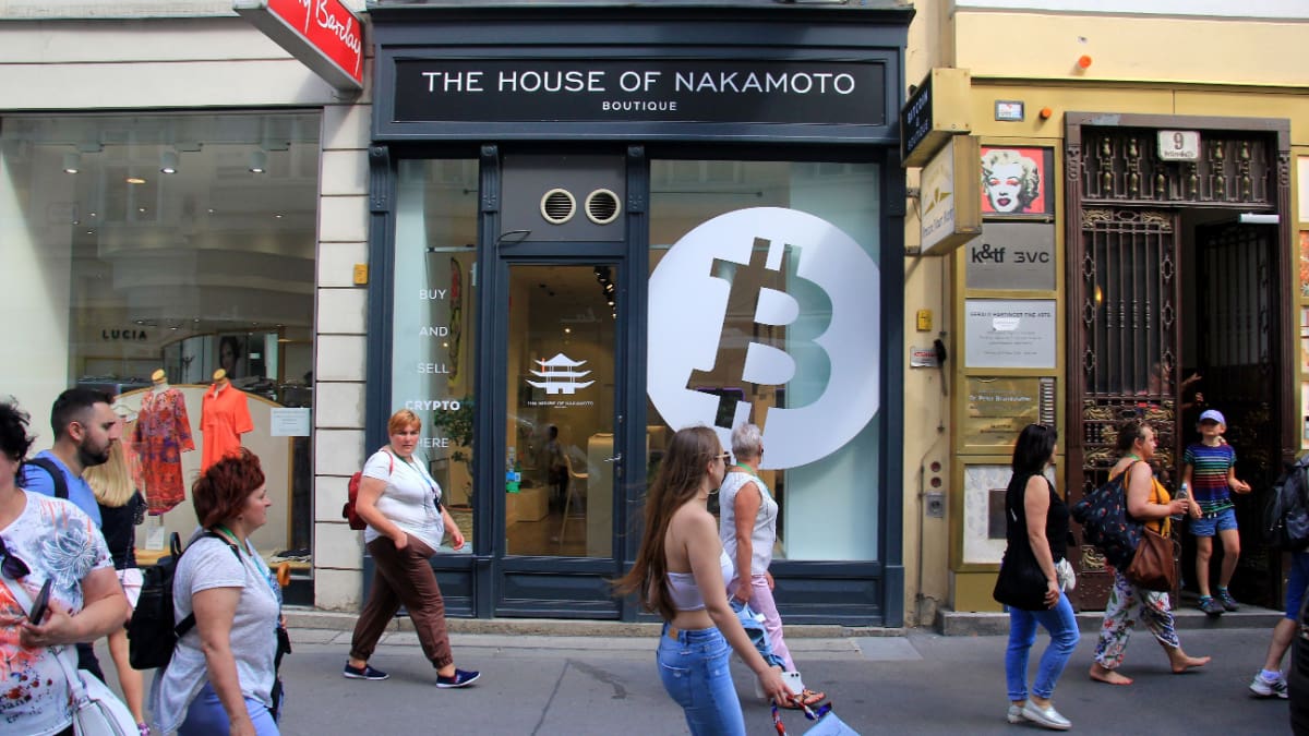 Een afbeelding van 'the house of nakamoto' met een bitcoin logo op de gevel van een winkel _ huis