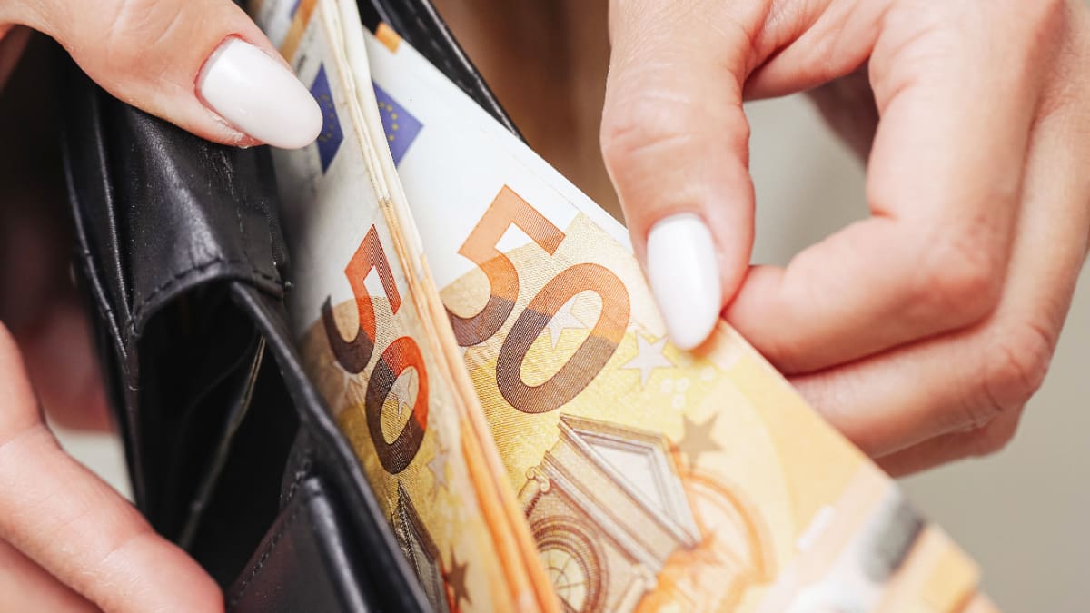 Een afbeelding van vrouwelijke handen die briefjes van 50 euro uit een portemonnee trekken